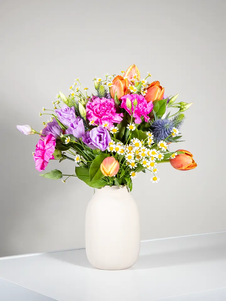 Bouquet tulipani arancio camomilla lisianthus lilla eryngium in vaso beige